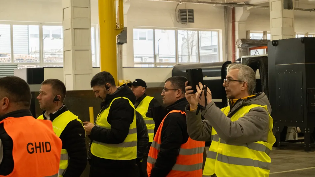 Un ghid Moduline în vestă portocalie explicând o etapă de producție vizitatorilor