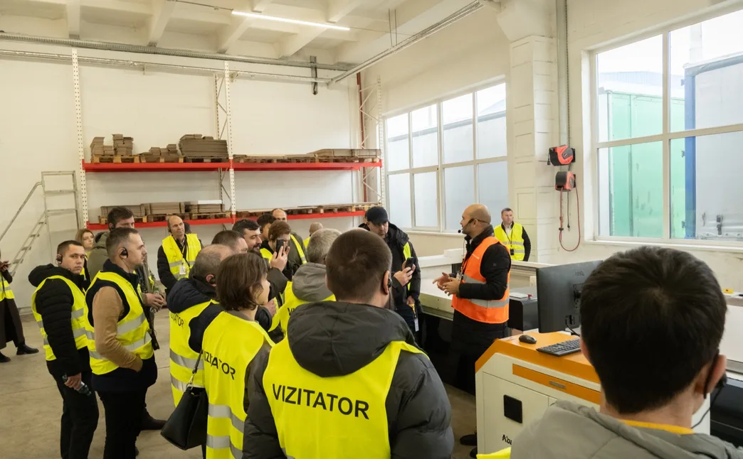Grupul în jurul unui post de lucru din hala de producție